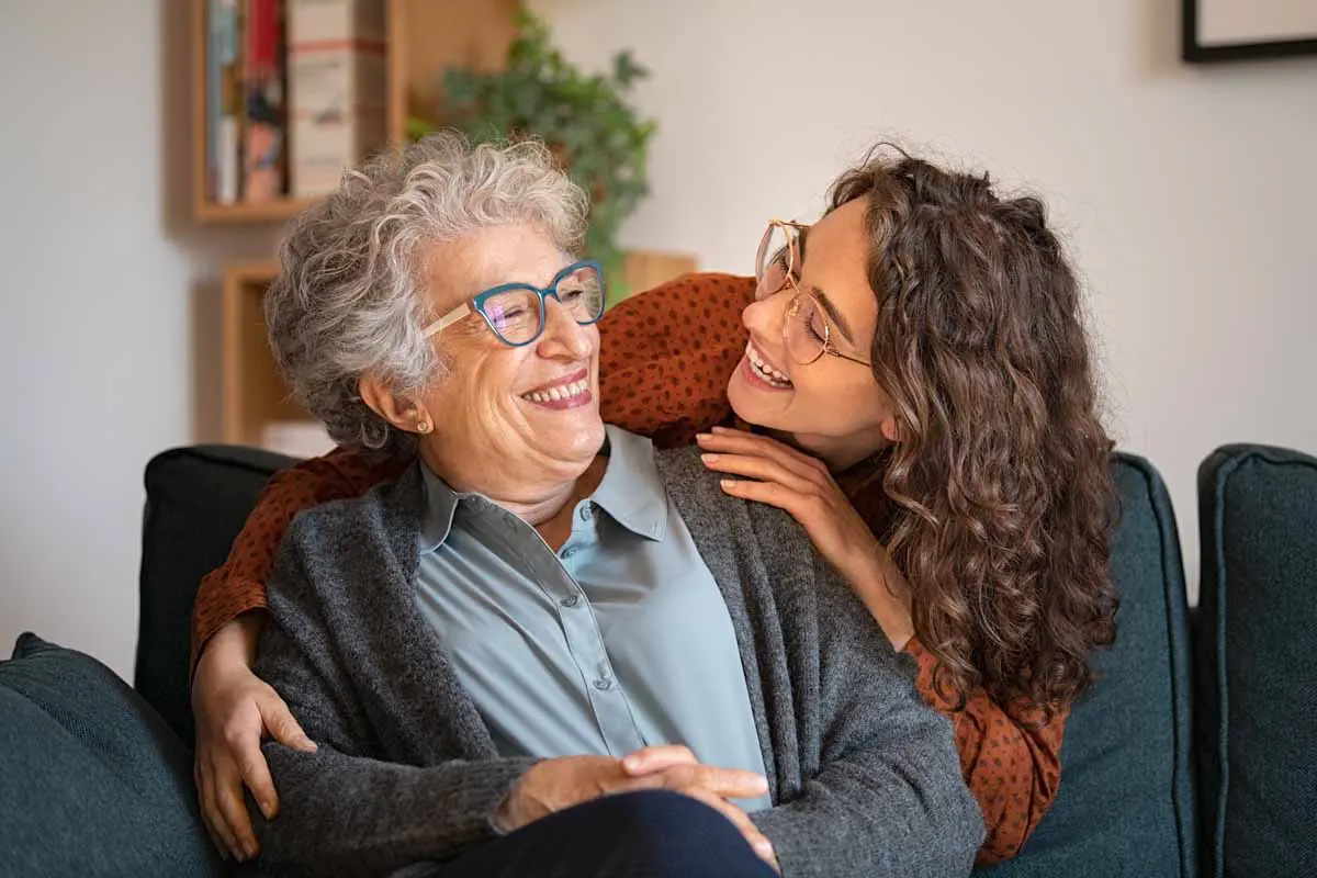 A daughter and her mother smiling together at home